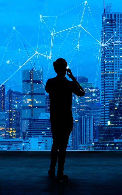Building an agile digital workplace for an AI world - showing silhouette of a business man on mobile overlooking a network overlayed across a skyline