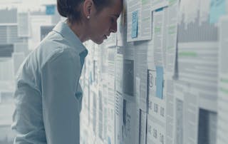 Woman with head against data printouts covering the entire walls - Addressing UC monitorings biggest pain point turning data overload into insights blog
