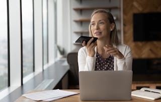 Image of business woman at desk talking into her mobile phone
