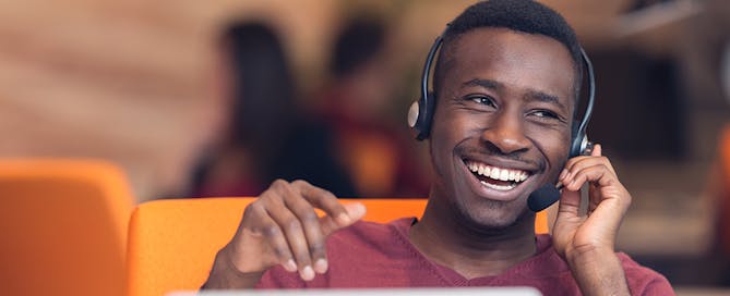 Cisco Prime Collaboration replacement - Happy man using headset with laptop at desk