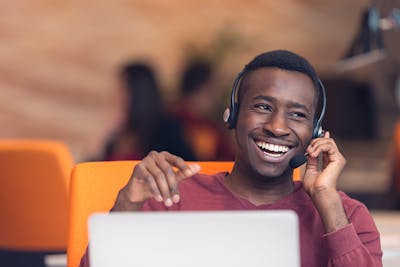 Cisco Prime Collaboration replacement - Happy man using headset with laptop at desk