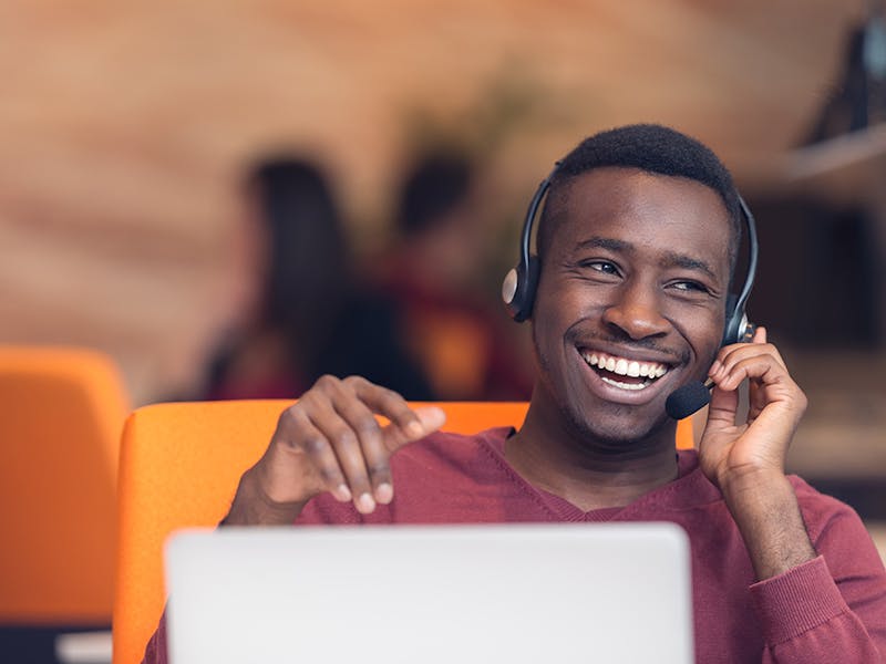 Cisco Prime Collaboration replacement - Happy man using headset with laptop at desk