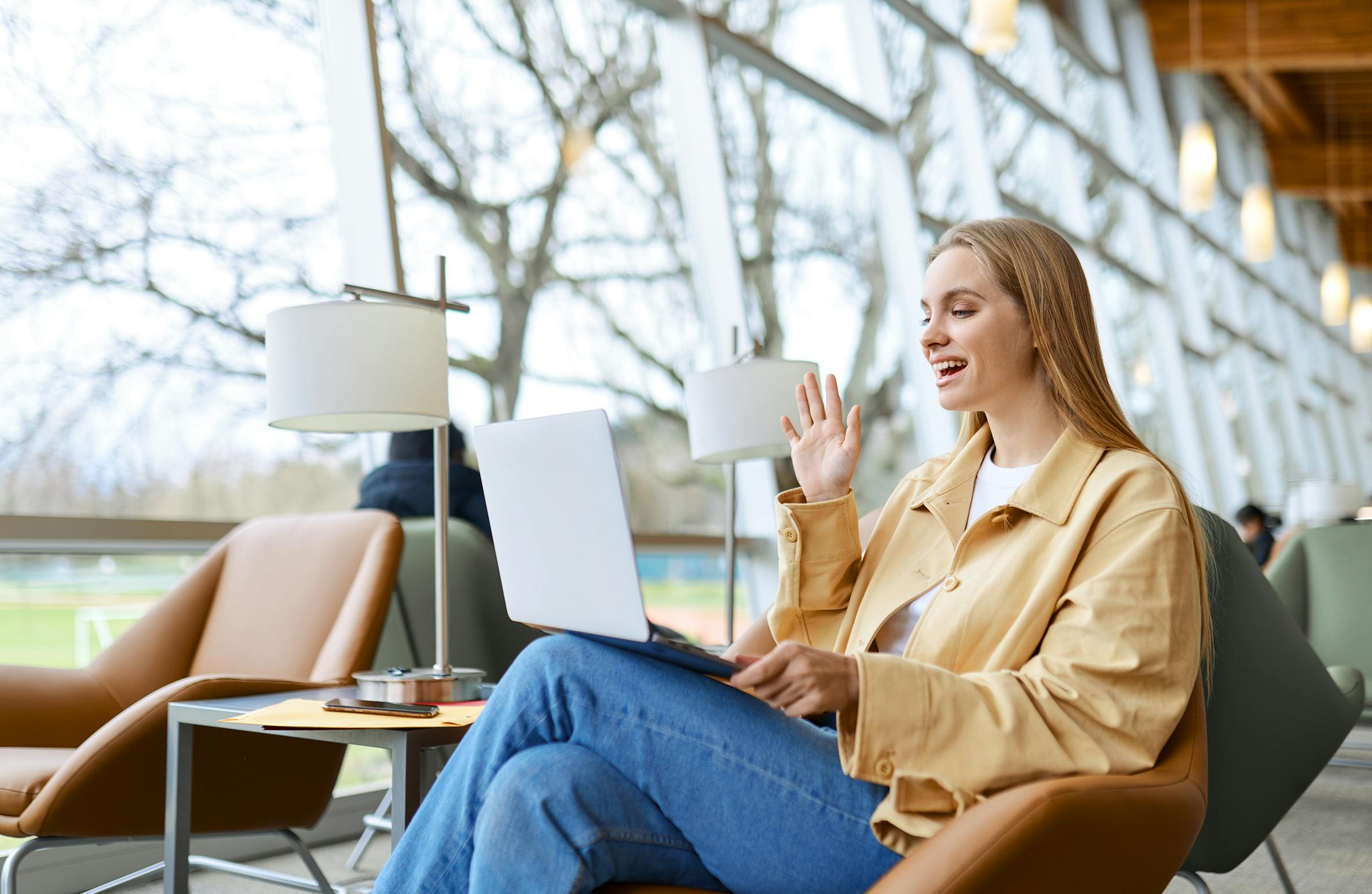 Young woman having a meeting in a public area on a laptop - multi-vendor hybrid office meeting room experience