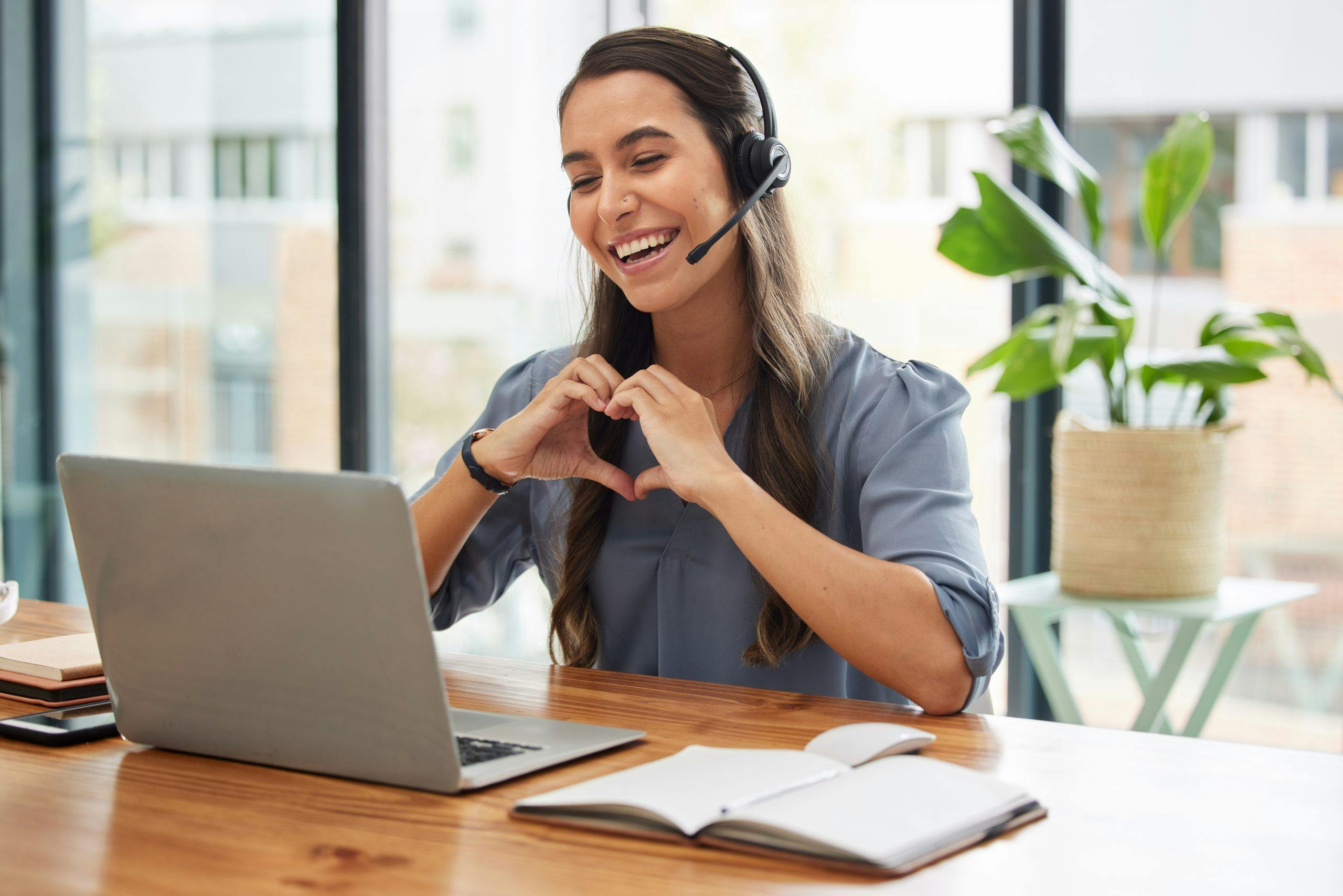 Happy user experience. Woman makes heart shape with hands. VOSS Insights contributes to a seamless and high-quality user experience across your UC environment.