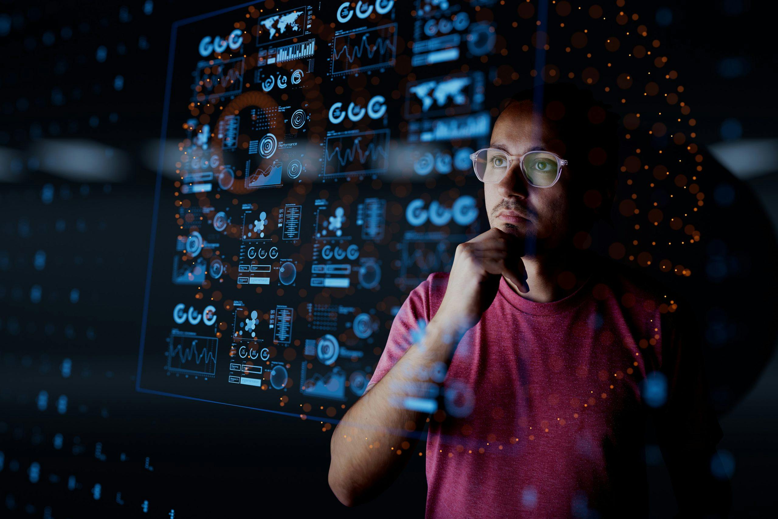 Dark background of Analyst looking at graphical data - used in VOSS blog for Maximizing Business Value with AI in UC: Cost Efficiency and New Opportunities