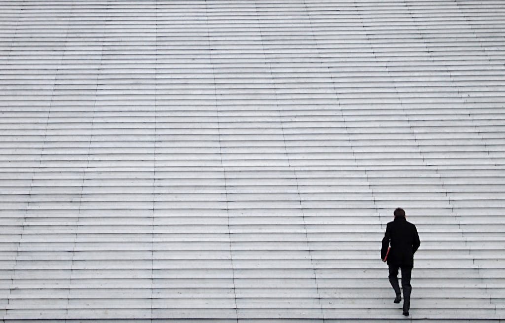 Man has a long walk to the top of wide stone stairs