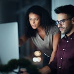 Business people, computer and night team work with planning, collaboration or problem solving at tech company. Developer, programmer and leader with serious for software support and web solution