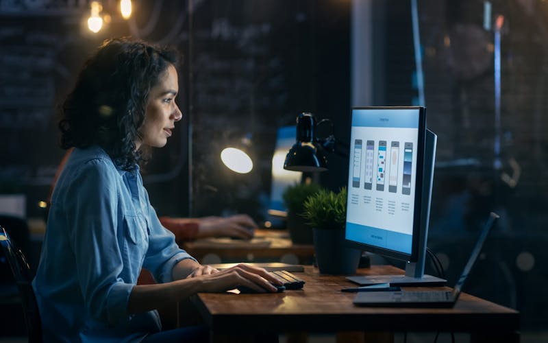 A woman working at a computer in an office, using software to improve productivity and teamwork.