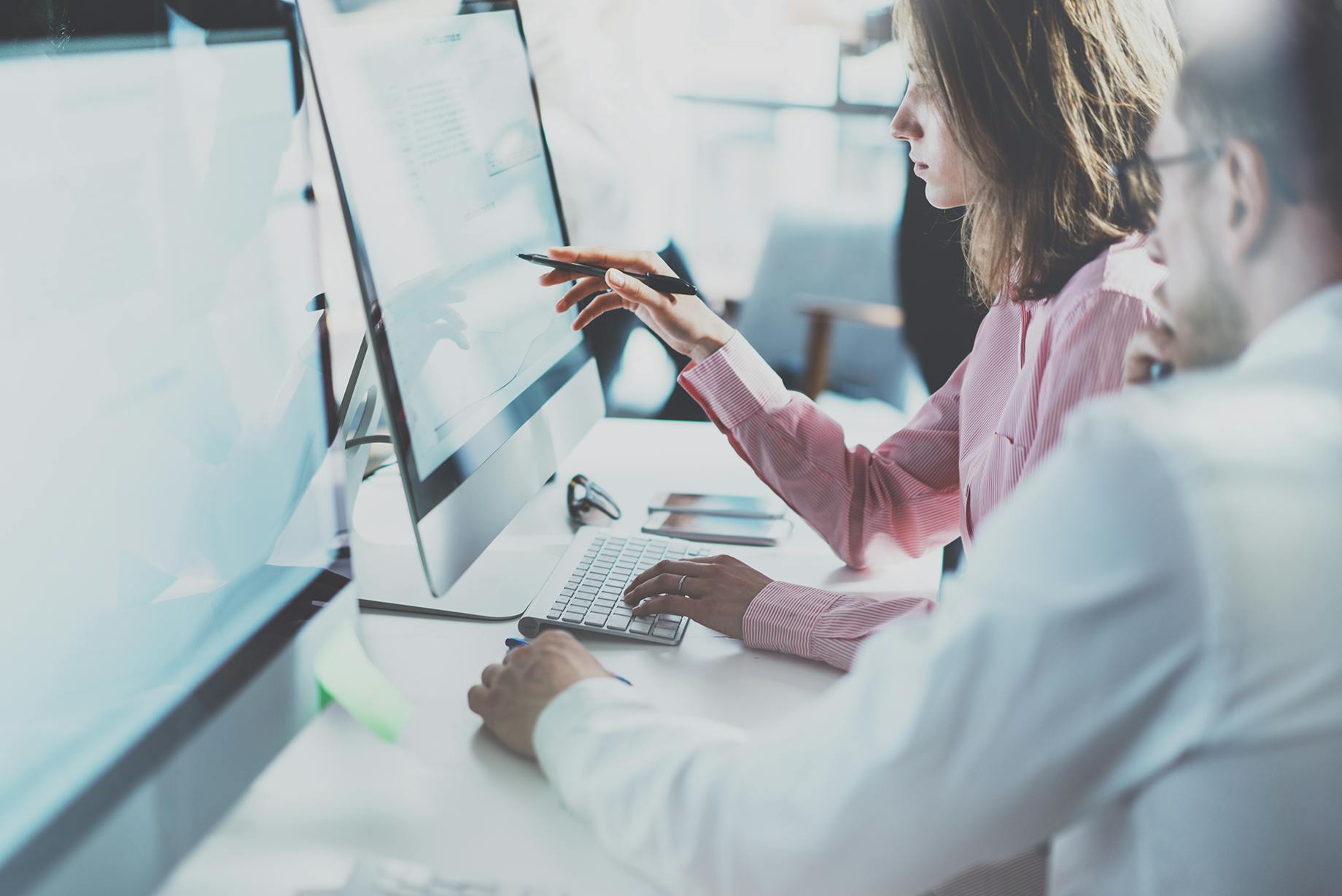Office workers at desk looking at monitor - VOSS Insights monitoring and resolution banner