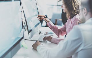 Office workers at desk looking at monitor - VOSS Insights monitoring and resolution banner